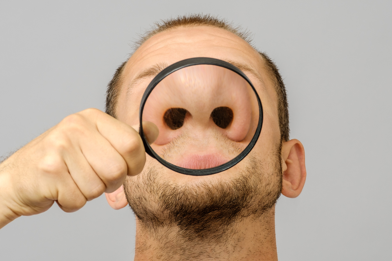 Portrait of caucasian man with magnifier makes fun face. Magnifier to the nose