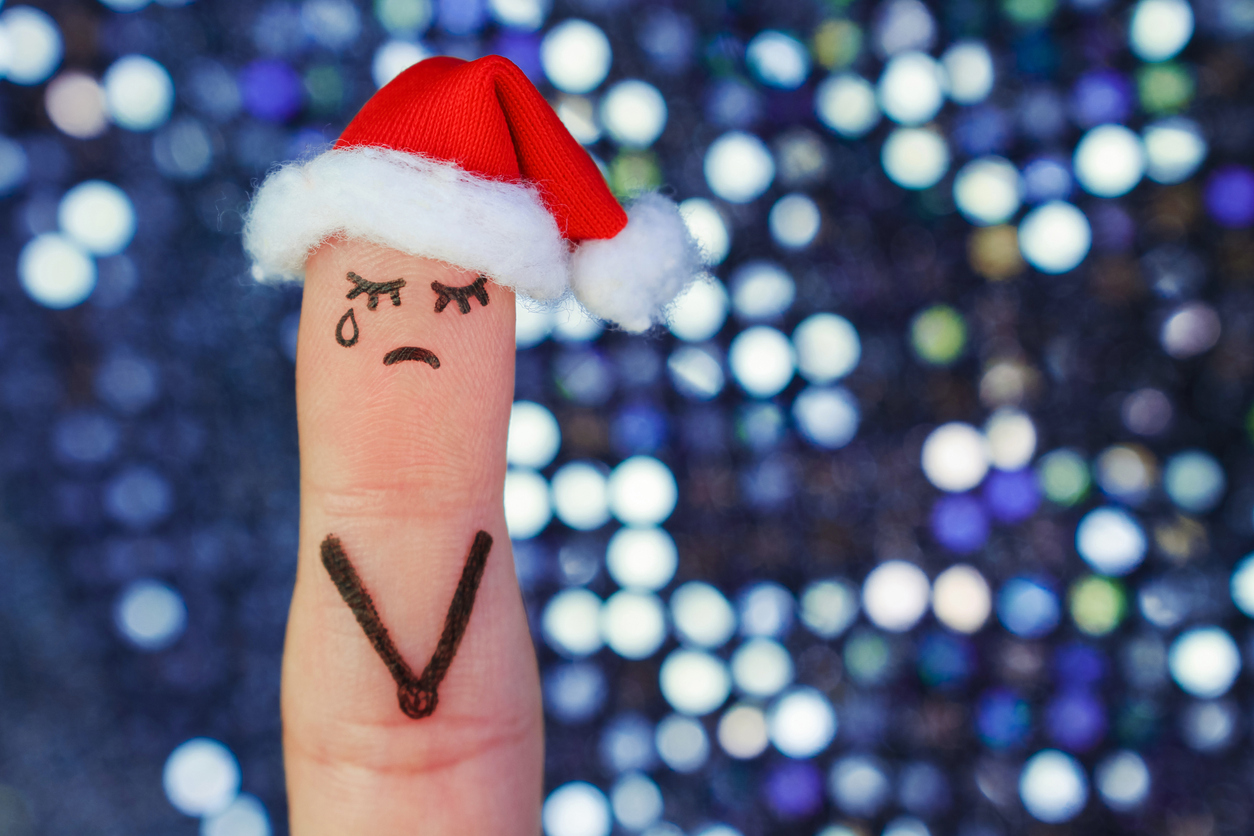 Finger art of lonely woman is crying. Concept people celebrate Christmas in new year hat. Toned image.