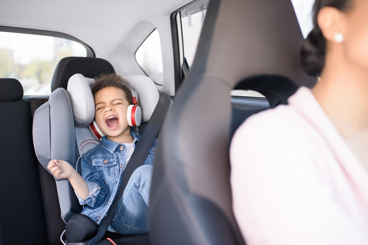 little african american girl listening music with mother sitting in car